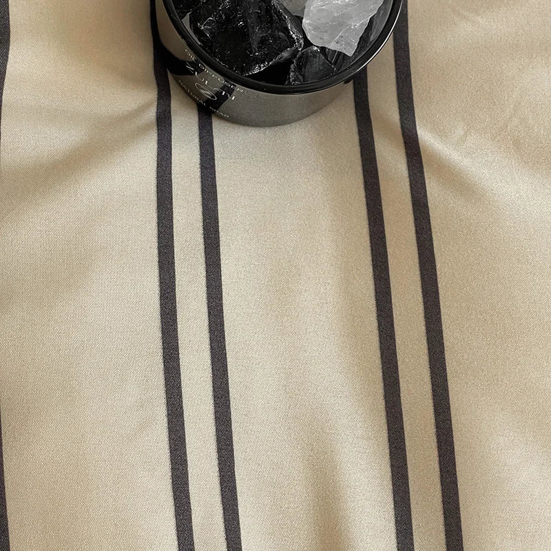 Close-up of a duvet cover with black stripes and a black container with stones on top.