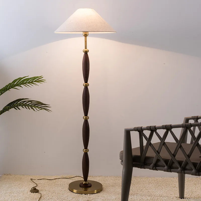 Floor lamp with wooden and brass design in a room setting.