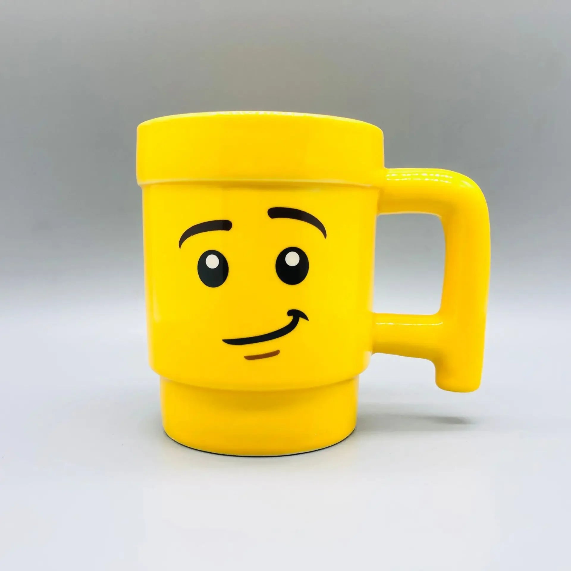 Yellow mug with a smiley face design on a grey background