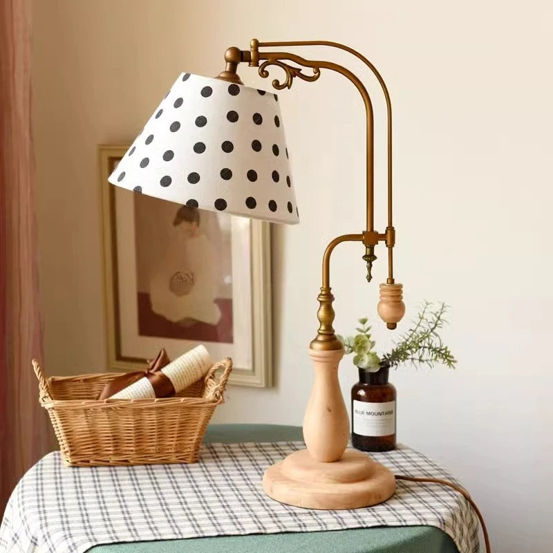 Wood and brass table lamp with black polka dot fabric shade on a styled table