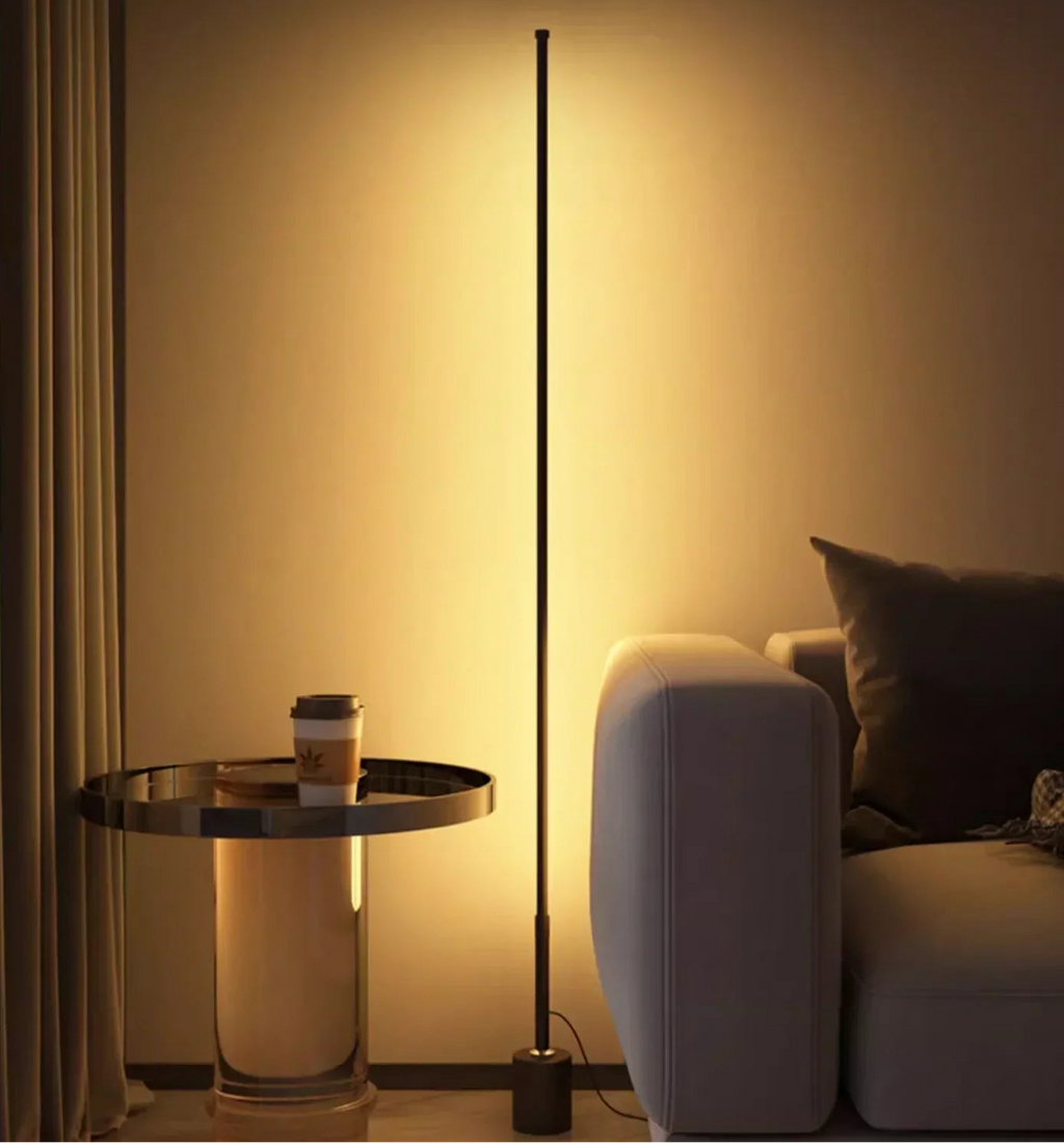 Slim black LED floor lamp casting warm ambient wall light