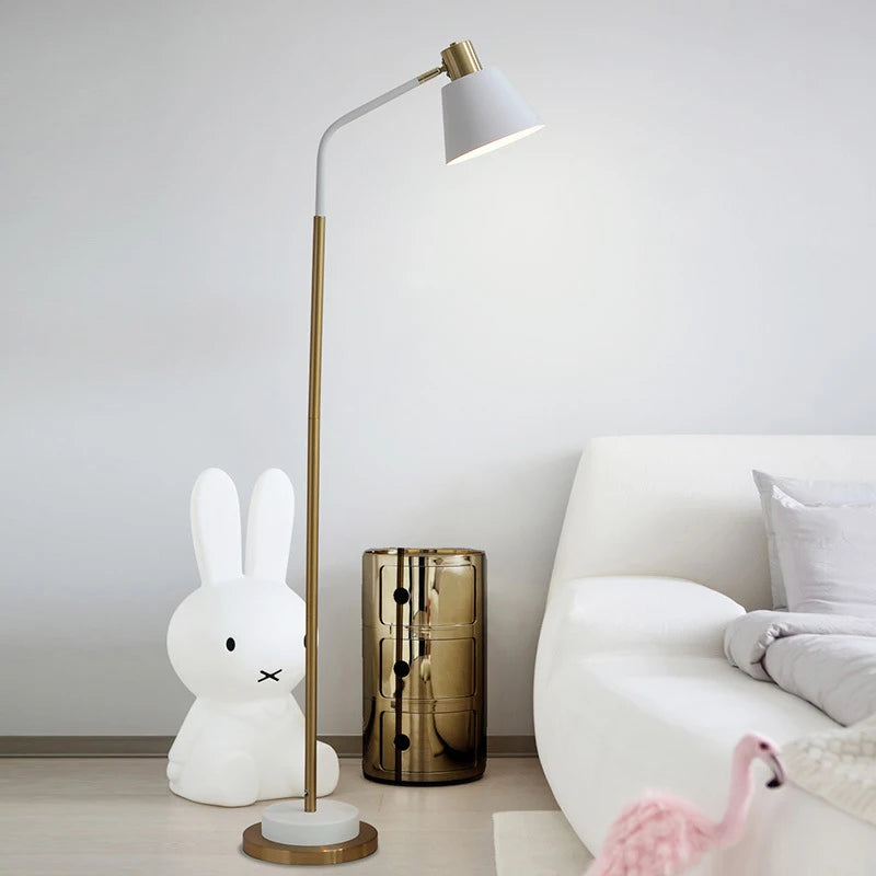 White Nordic Floor Lamp — White Nordic-style metal floor lamp with gold-tone stem, angled shade, and round base.