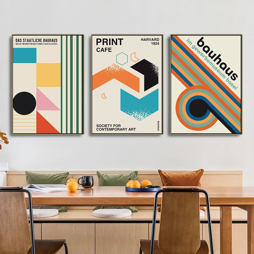 Three colorful posters on a wall above a dining table with chairs.