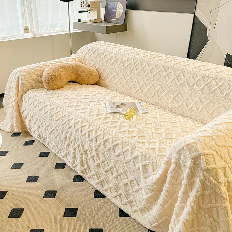 Beige textured throw blanket draped over a sofa in a room with a geometric floor pattern.