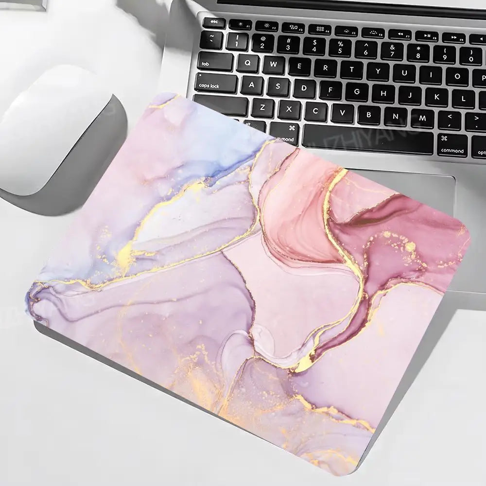 Marble-patterned mouse pad on a desk with a laptop and mouse.