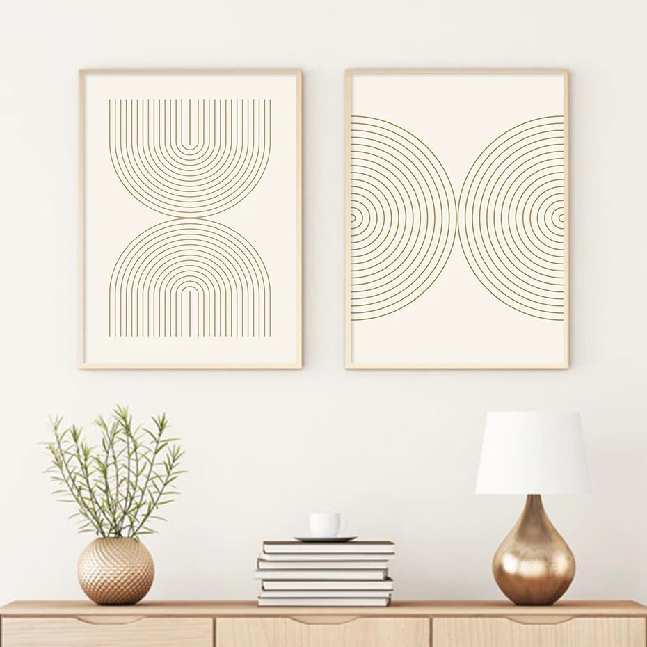 Two abstract wall art pieces on a white wall above a wooden console table with decor items.