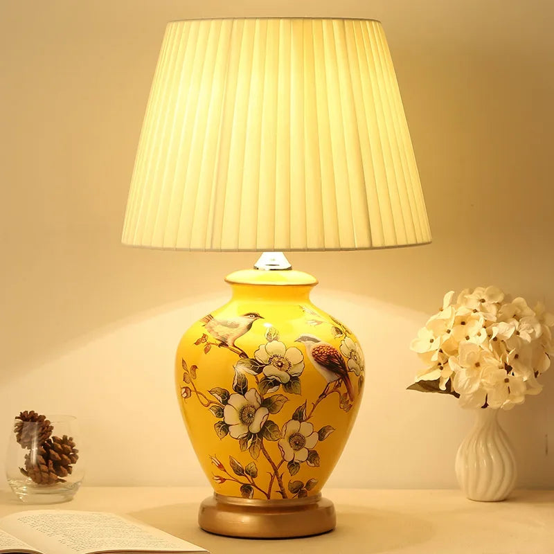 Decorative table lamp with floral design on a yellow base, illuminated in a warm setting.
