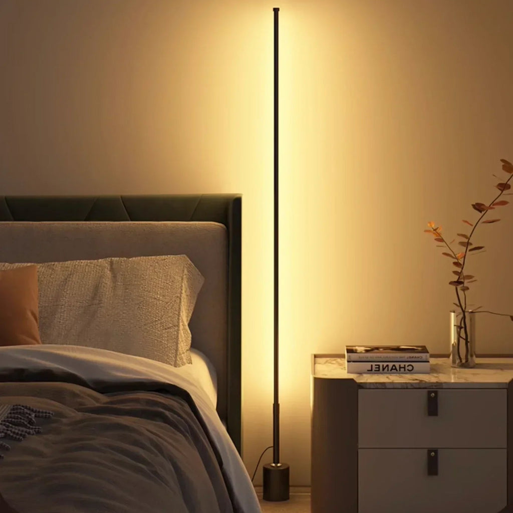 Slim black LED floor lamp casting warm ambient wall light