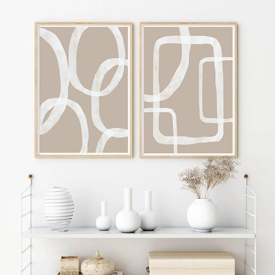 Two abstract wall art pieces on a white wall, with decorative vases below them.