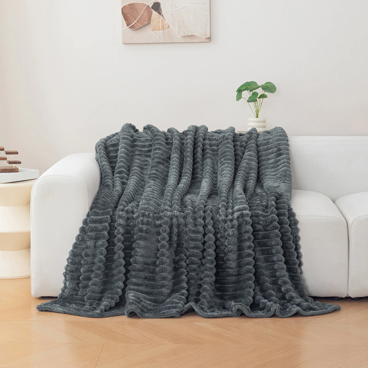 Charcoal grey textured blanket draped over a white sofa in a living room setting.