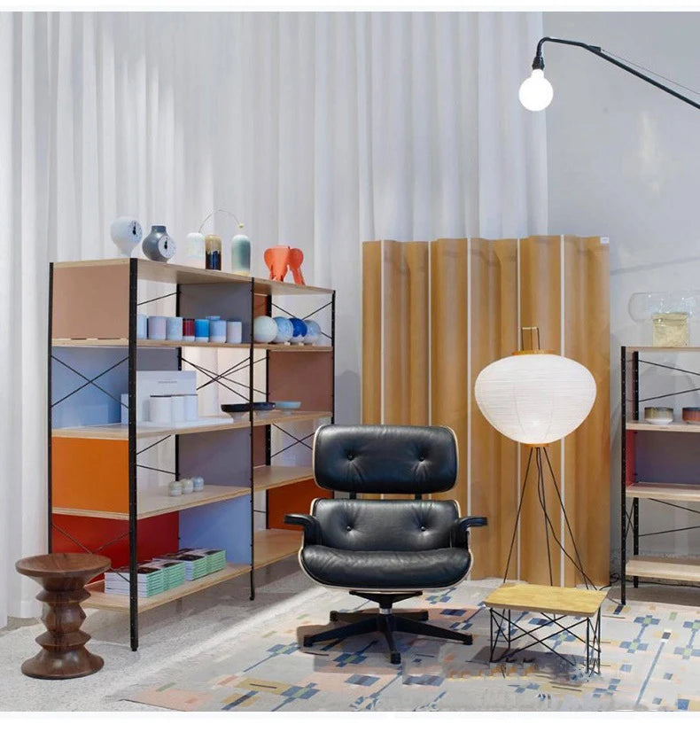 A Japanese floor lamp in a living room with a black leather chair, colourful bookshelf, and a standing lamp.