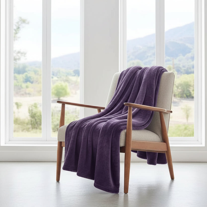 Purple blanket on a bed with a window view of greenery