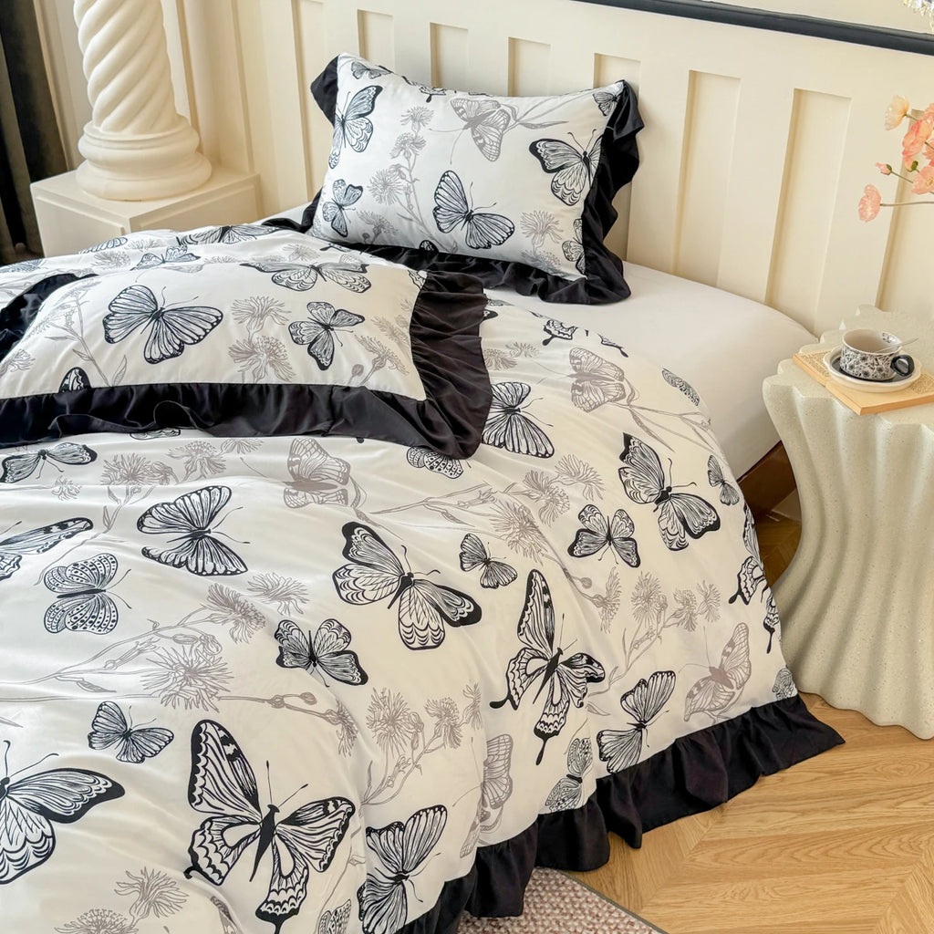 Detail shot of the matching butterfly pillowcases with black ruffled borders, styled on a bed with a minimalist side table.