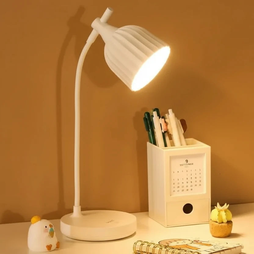 White desk lamp on a table with a pen holder and small decorative items against a warm brown background