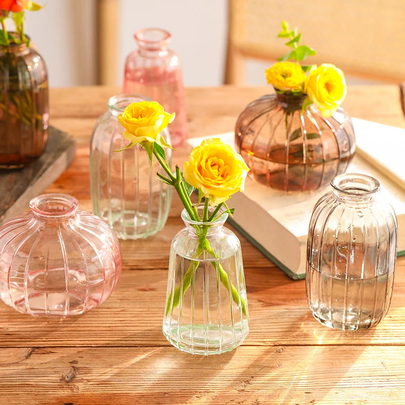 Clear glass vases with yellow flowers on a wooden table