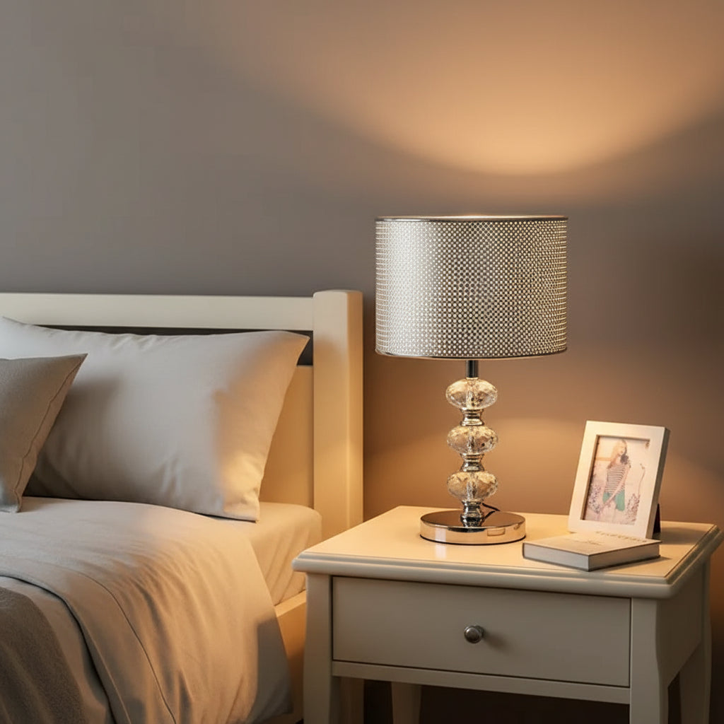 table lamp with a solid black cylindrical shade and a triple-stacked crystal base on a nightstand.
