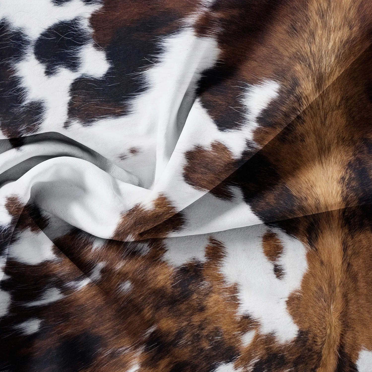 Close-up of a fabric with brown, white, and black cow print pattern.