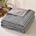 Black and white gingham quilted comforter with a grey border, folded on a bed
