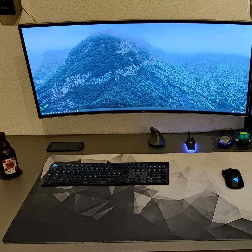 Computer setup with dual monitors displaying mountain scenery on a desk.