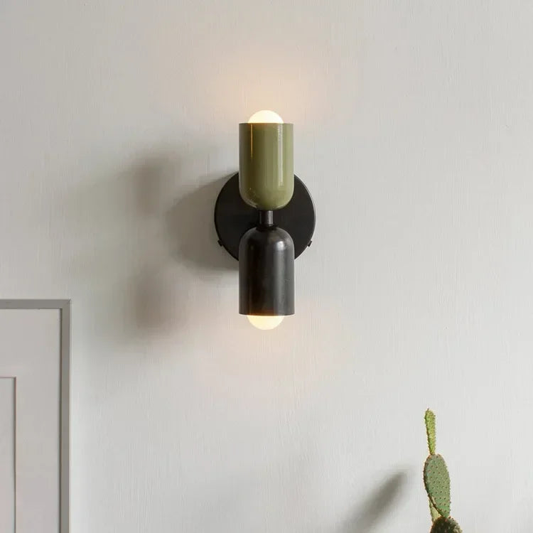 Modern wall sconce with green and black design on a neutral wall.