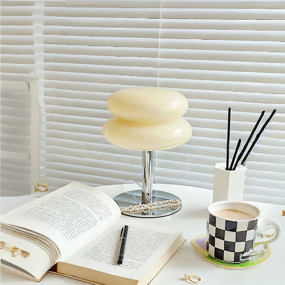 A modern cream colour table lamp against a window with blinds.