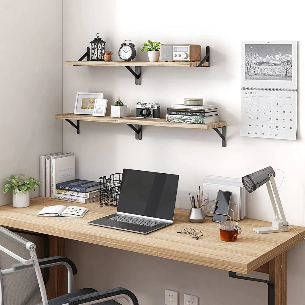 Home office setup with a wooden desk, laptop, lamp, and shelves on a white wall.