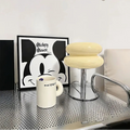 A cream coloured table lamp on a metal desk