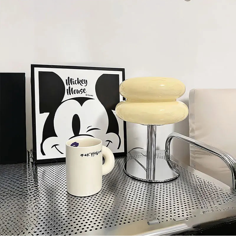 A cream coloured table lamp on a metal desk