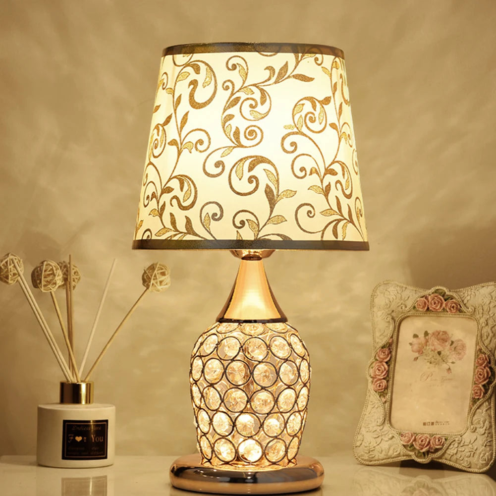 Elegant gold bedside lamp featuring intricate vine patterns on a white fabric lampshade.