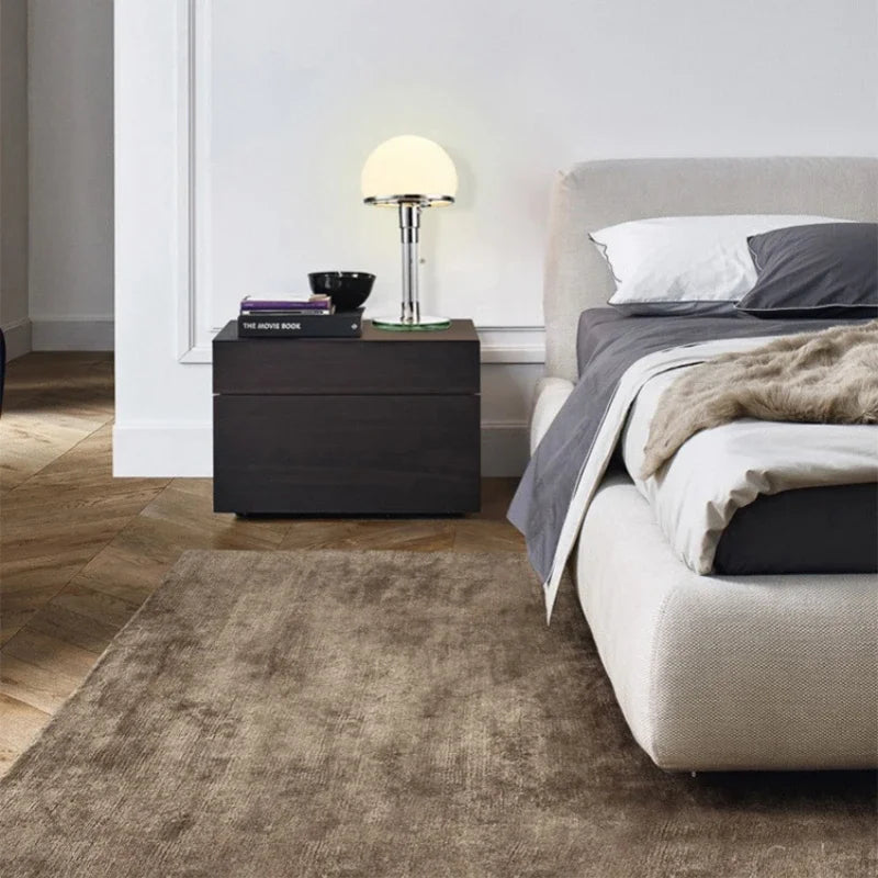 Modern bedroom with a bed, nightstand, and lamp.