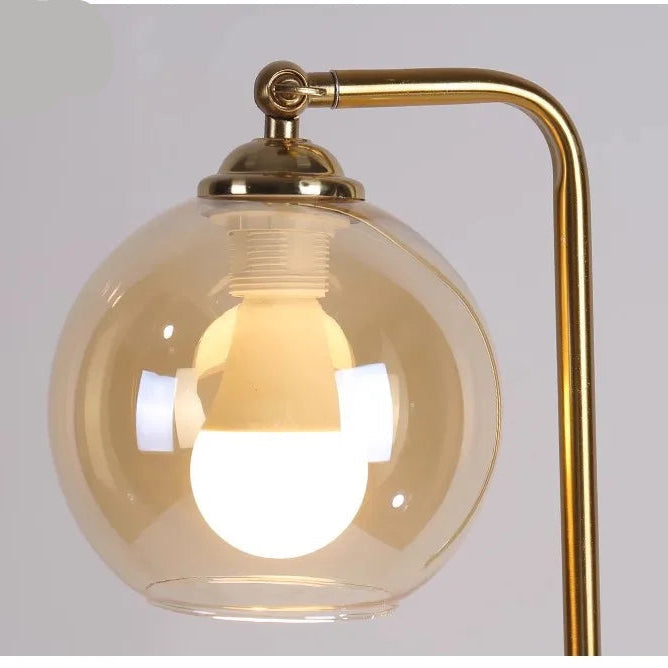 Gold floor lamp with a glass shade on a white background
