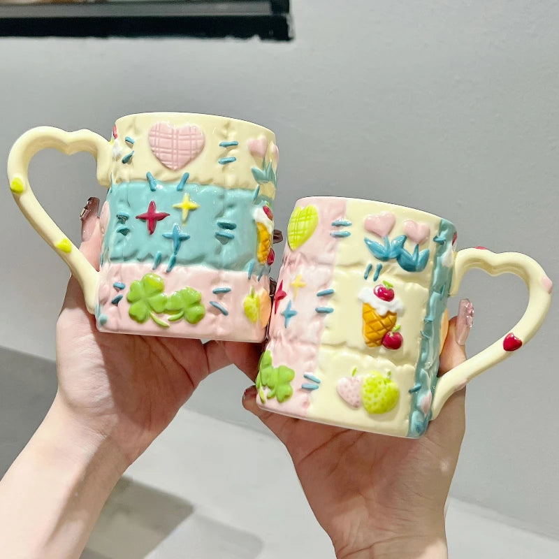 Two decorative mugs with colorful patterns held by hands against a neutral background