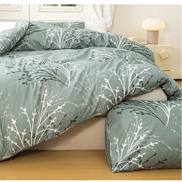 Sage green bedding set with soft botanical print styled in a bright minimalist bedroom