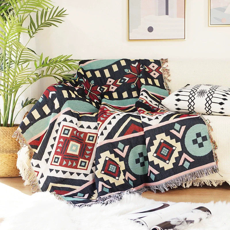 Noir Aztec patterned throw draped over a cream sofa with printed cushion