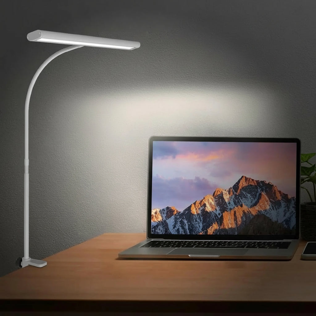 Desk setup with a lamp, laptop, and phone on a wooden surface.