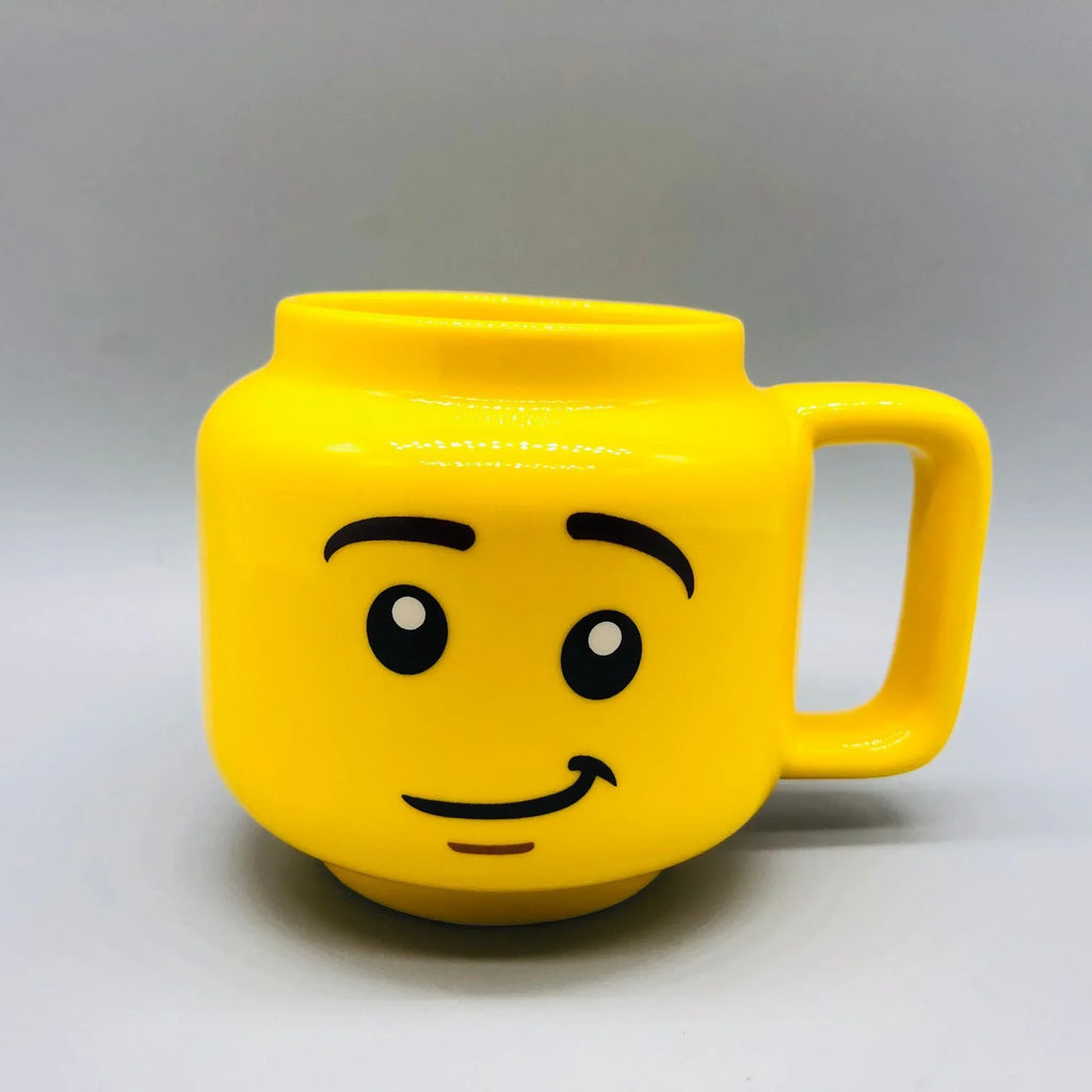 Yellow mug designed with a smiley emoji figure head on a grey background