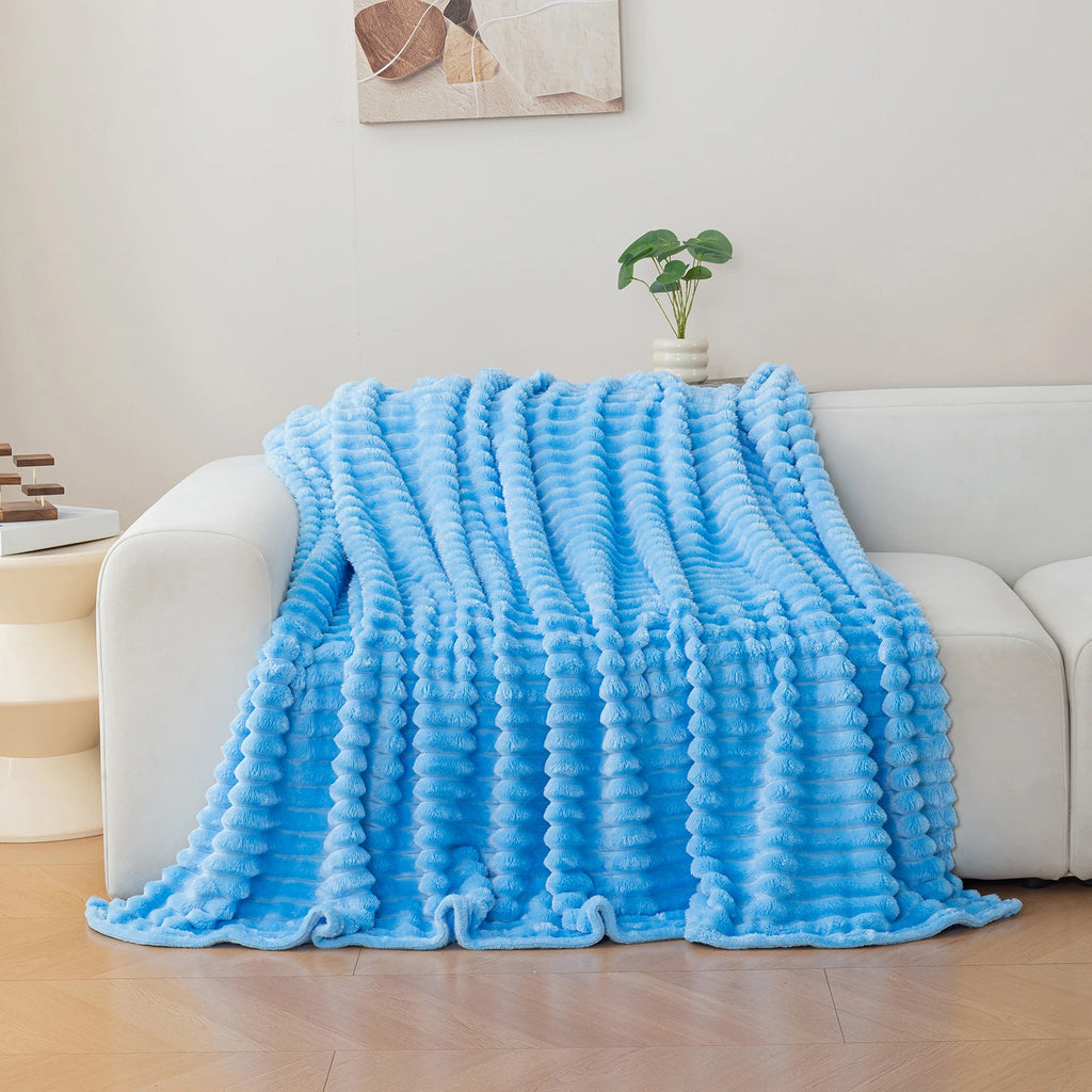 Blue textured blanket draped over a white sofa in a living room setting.
