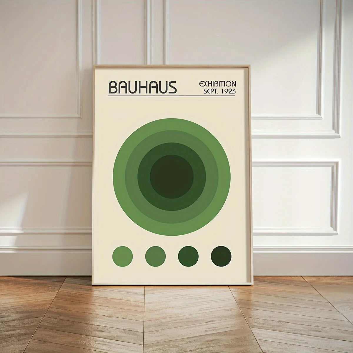 Bauhaus exhibition poster with green concentric circles on a beige background, framed and leaning against a wall.