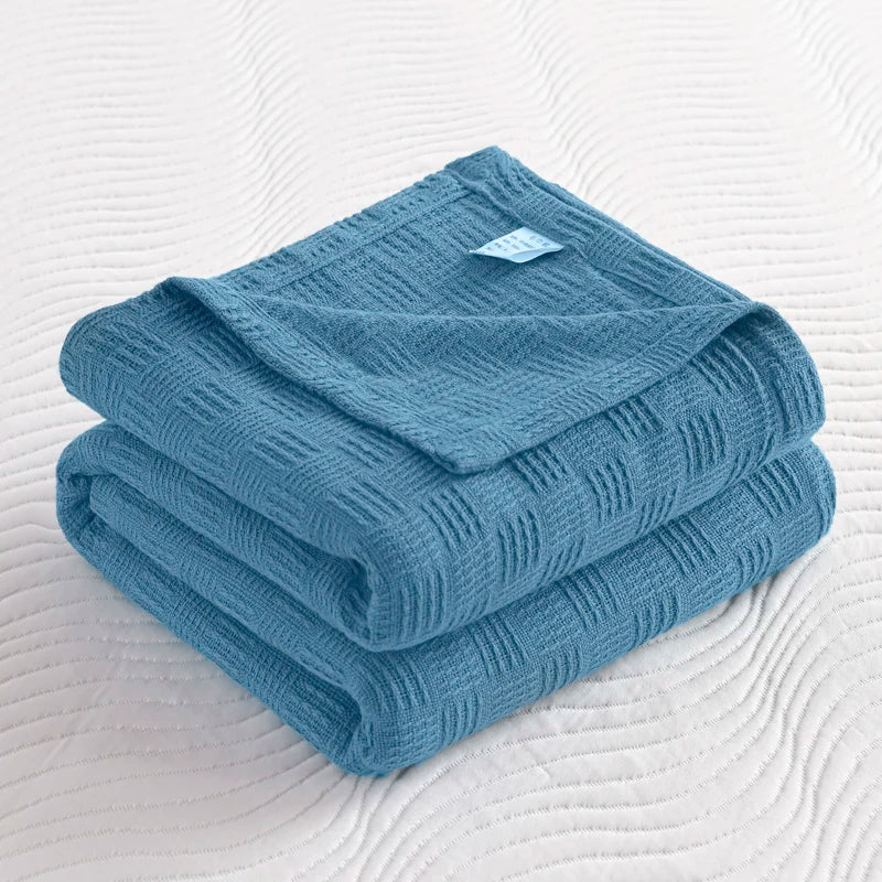 Folded steel blue cotton knit blanket with basket weave texture on white bedding