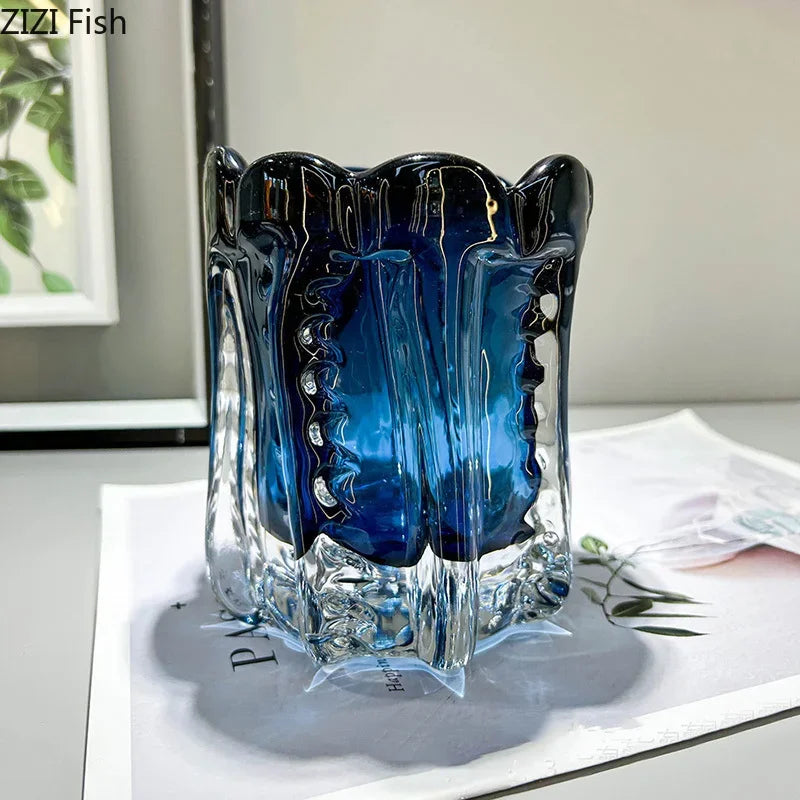 Blue and clear glass vase on a white surface with a blurred background
