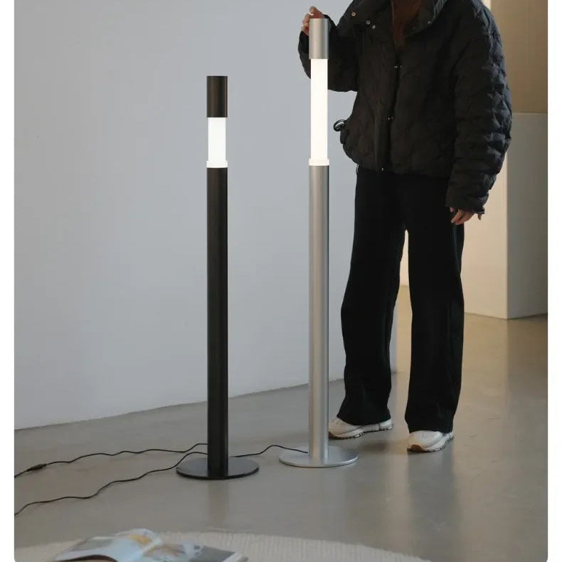 Person interacting with two modern floor lamps in a minimalistic setting