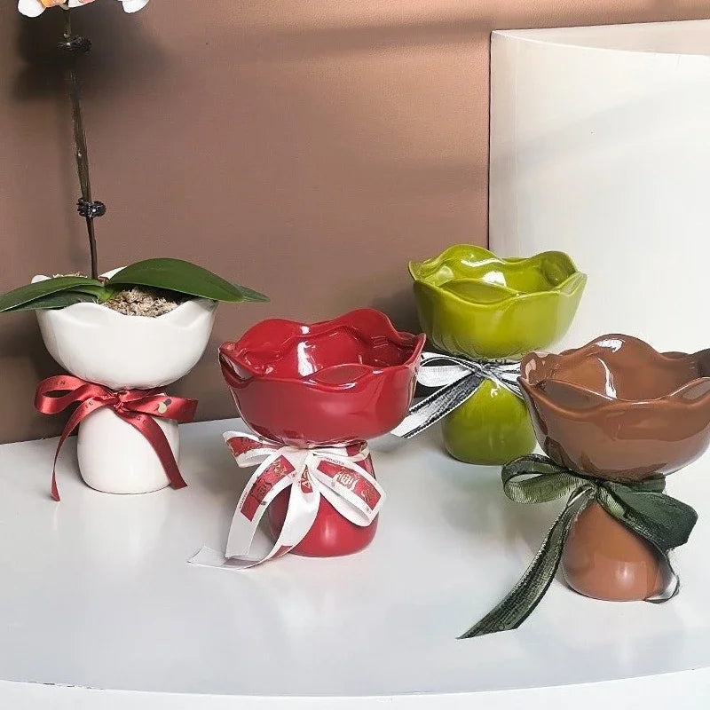 Four ceramic bowls in white, red, green, and brown with decorative ribbons on a white surface.