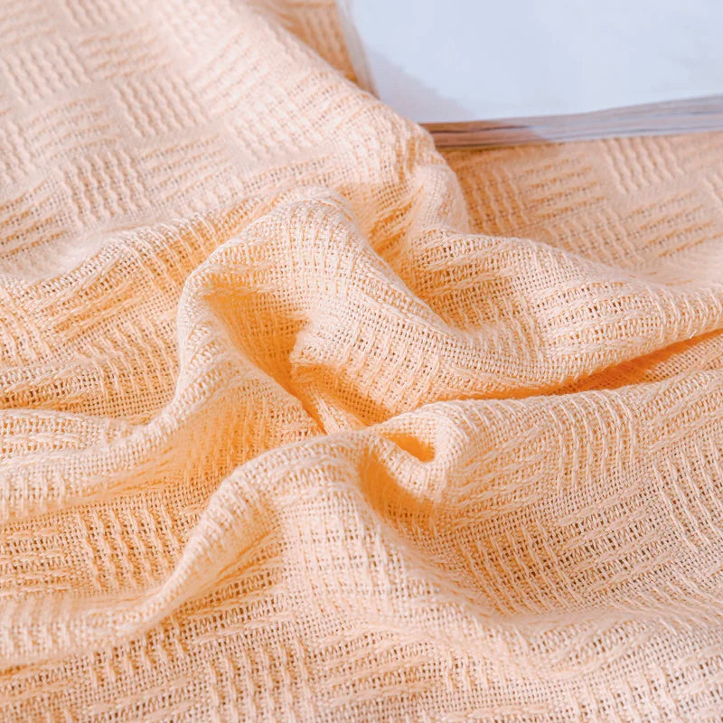 A cream cotton knit blanket with basket weave texture.