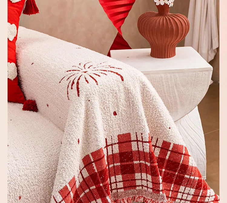 A cream-coloured quilted sofa cover featuring red fireworks and heart patterns with a checkered fringe.