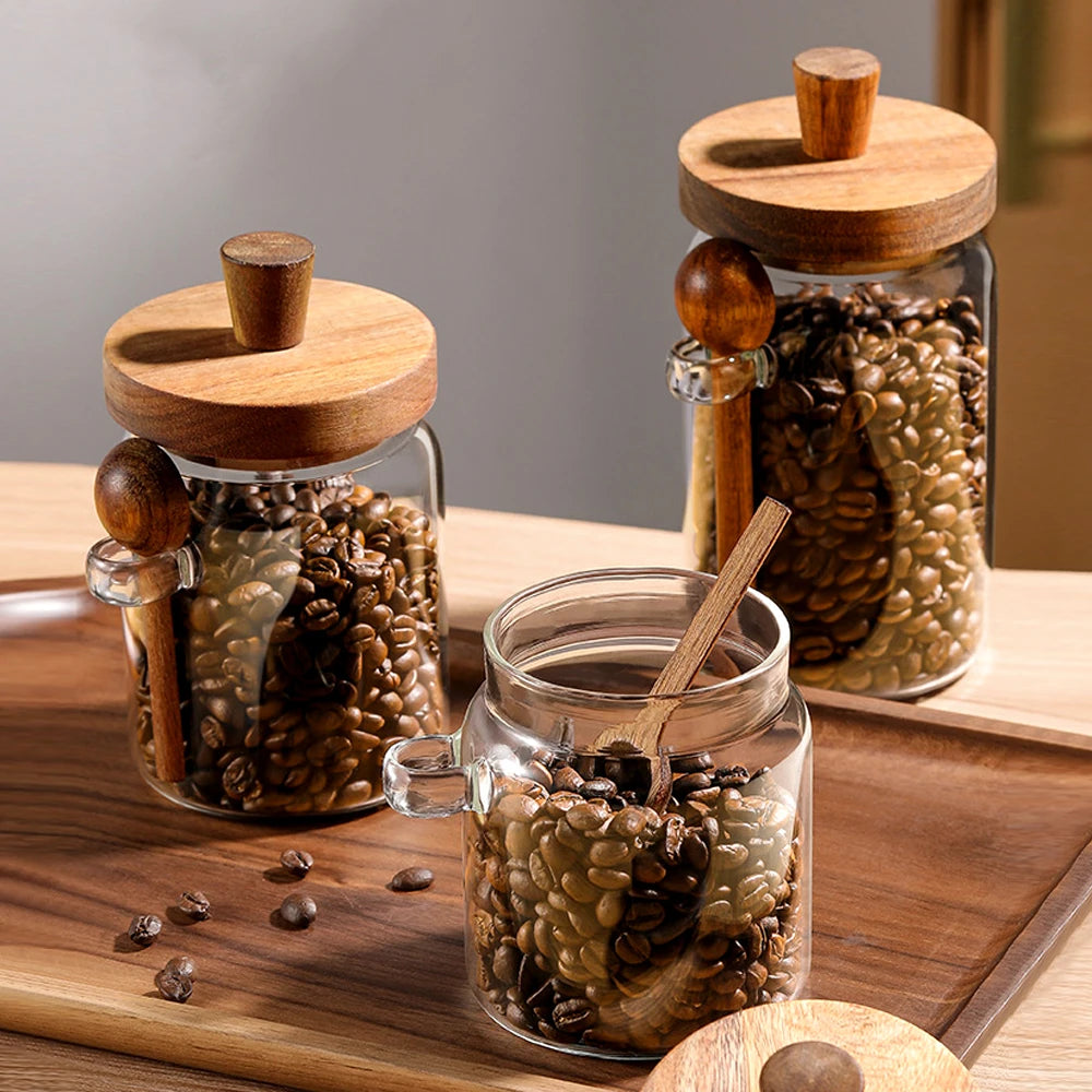 Three glass jars with wooden lids and handles on a wooden surface.