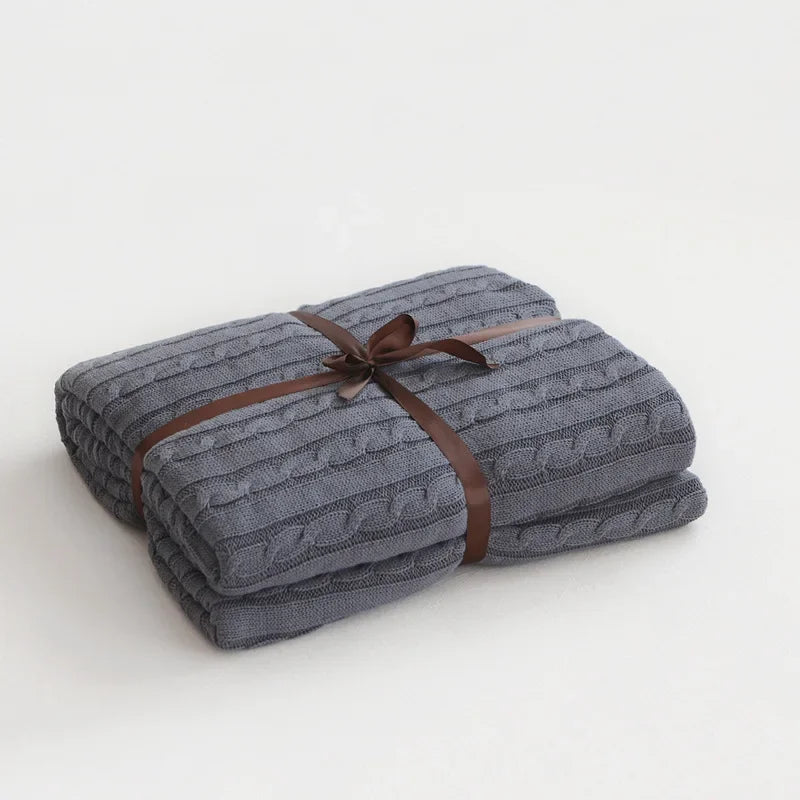 Folded gray textured blanket with a brown ribbon on a white background