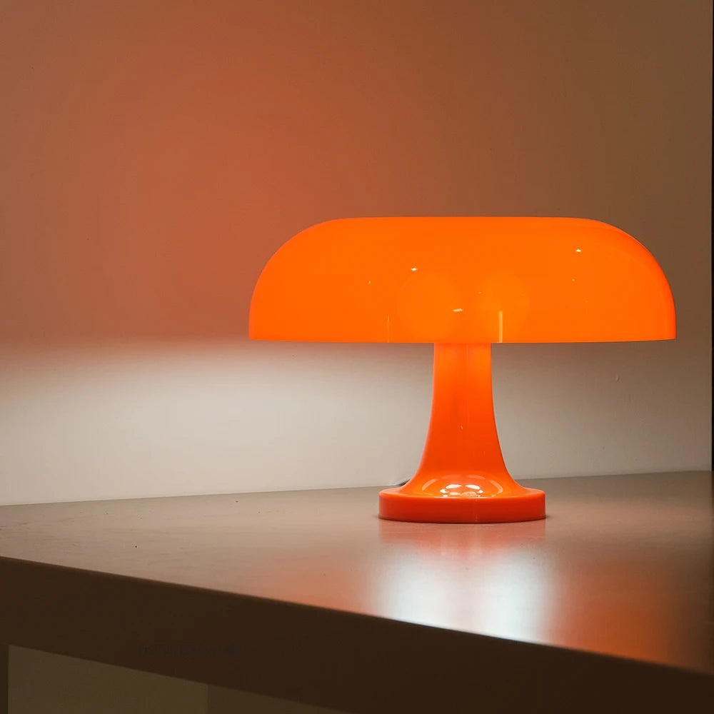Orange table lamp on a reflective surface with a warm background