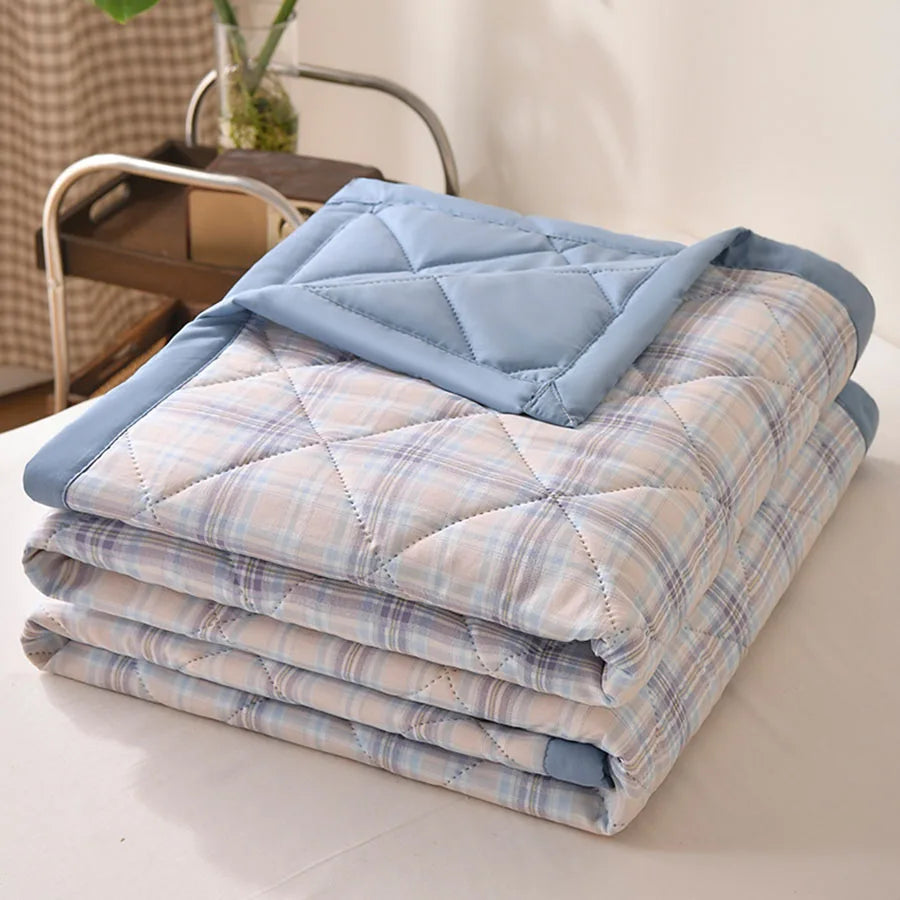 Blue plaid quilted comforter with yellow and beige lines and a blue border, folded on a bed
