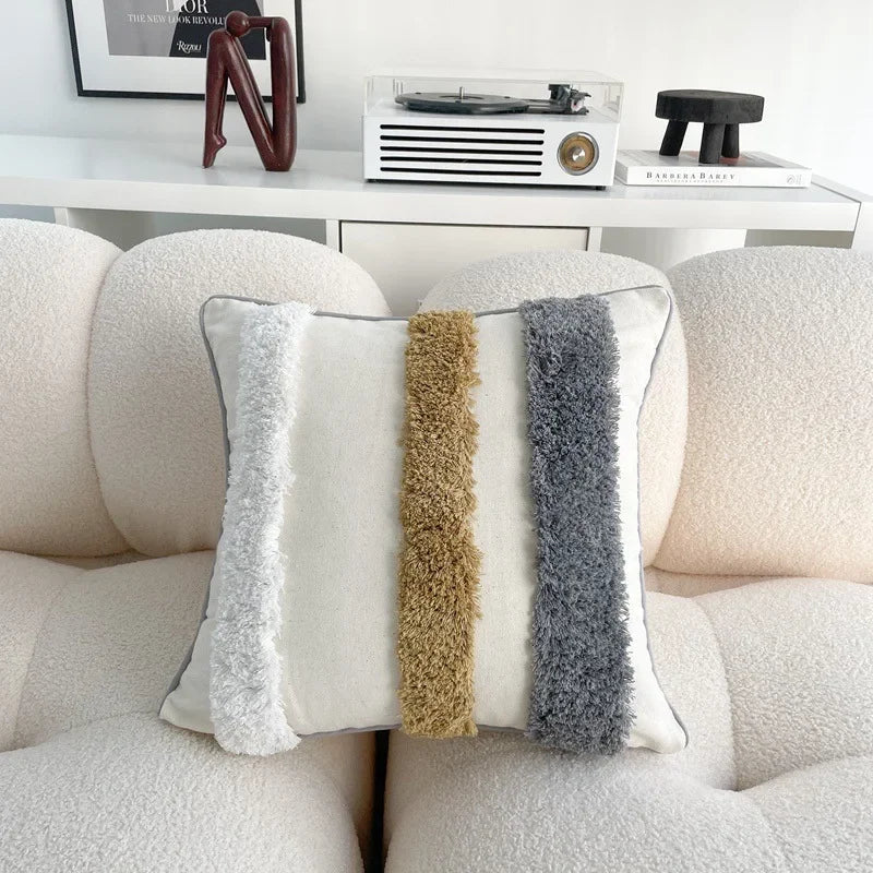 Decorative pillow with textured stripes on a beige sofa in a living room setting.
