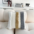 Decorative pillow with textured stripes on a beige sofa in a living room setting.